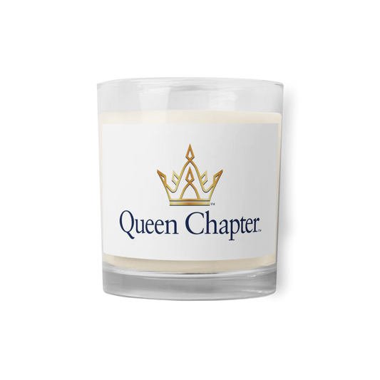 A glass candle with a white label that has the Queen Chapter logo printed on it.